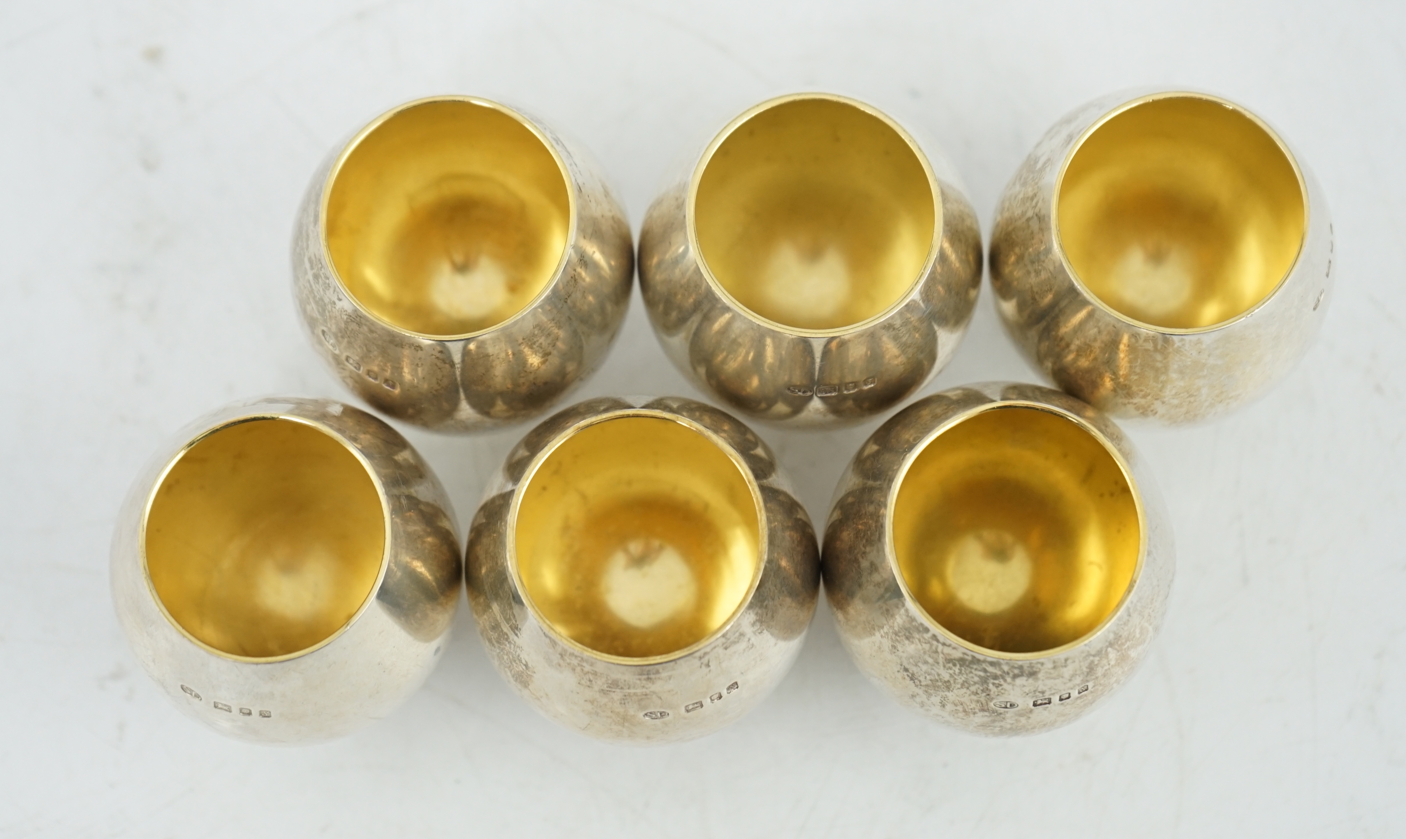 A set of six Elizabeth II Stuart Devlin parcel gilt silver balloon shaped pedestal tots